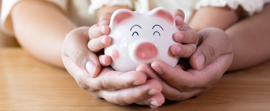 Parent and Child Hands with Piggy Bank
