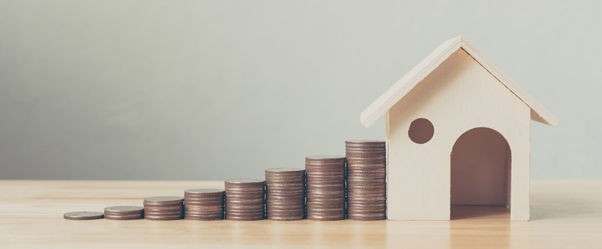 Coins stacking up to wooden house