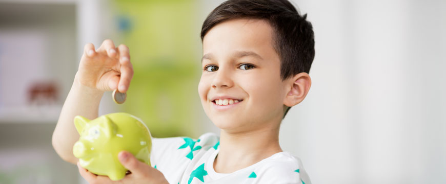 Child Putting Money in Piggy Bank