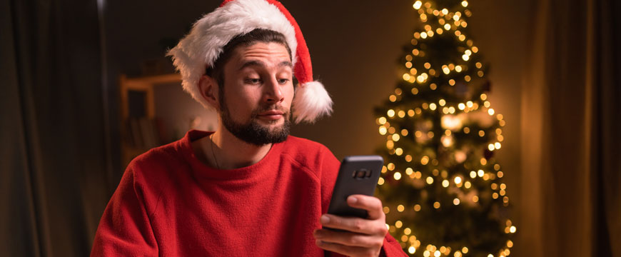 Guy with a Santa Hat, Looking at His Phone