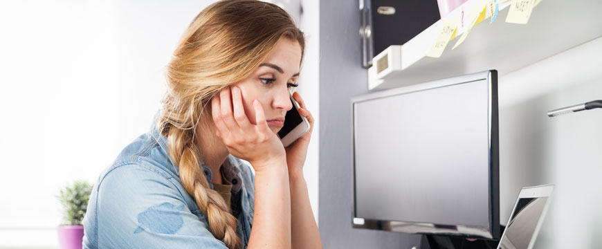 Girl on the phone and looking at a computer screen