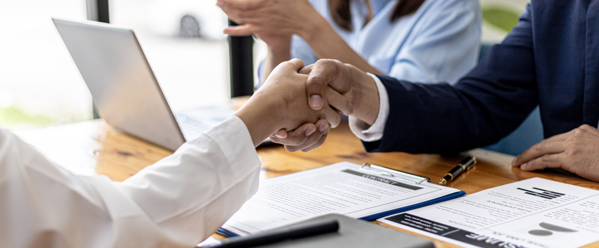 Two people shaking hands in a job interview setting