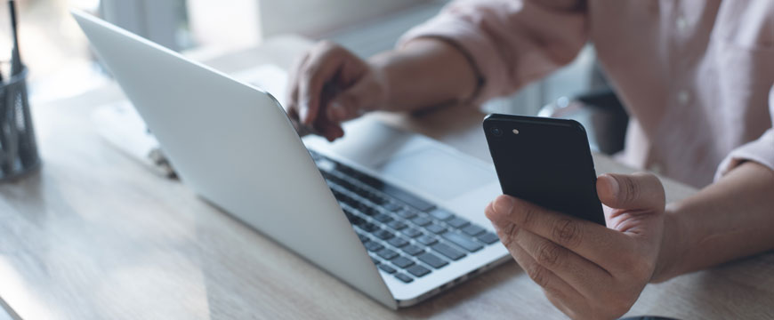 Person Looking at their Phone with a Computer