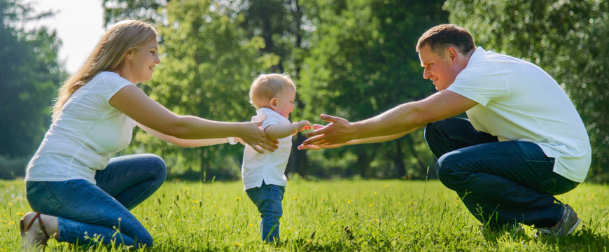 Having a Child, New Parents with outstretched arms as a toddler walks between them