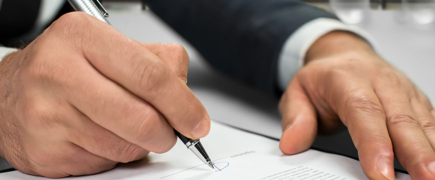 Medallion Signature Guarantee, image of a man's hands with a pen signing papers