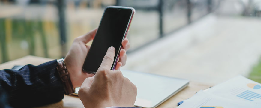 Hand Holding a Phone at a Desk