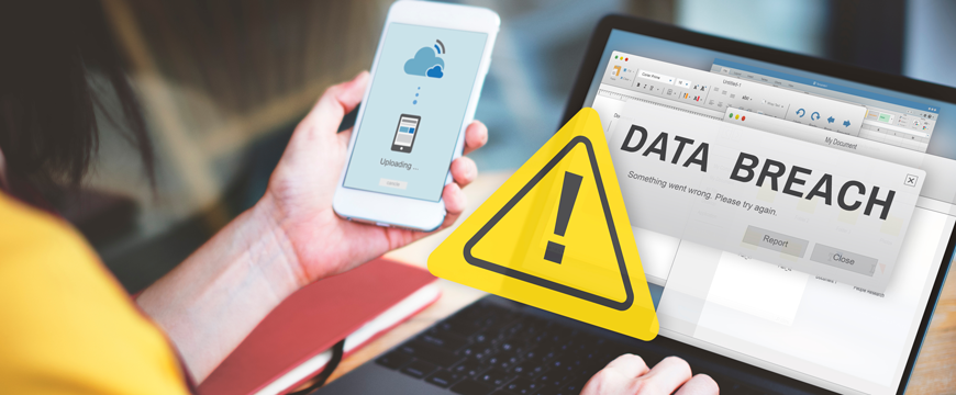 Hand Holding Phone and Working on a Computer Detecting a Cyberattack