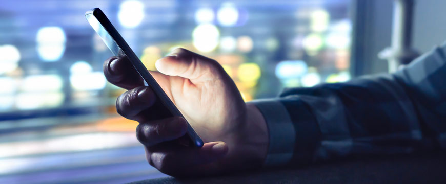 Person's Hand Holding a Phone in a Dark Room