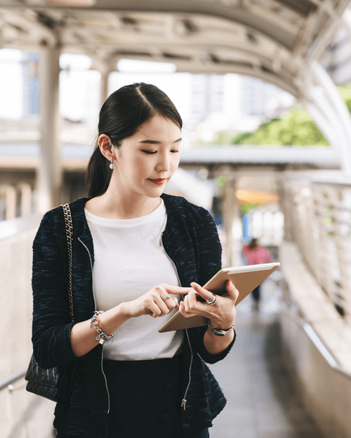 Woman using tablet while walking over bridge