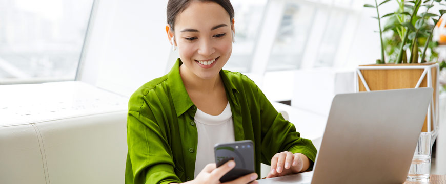 Woman using phone and laptop