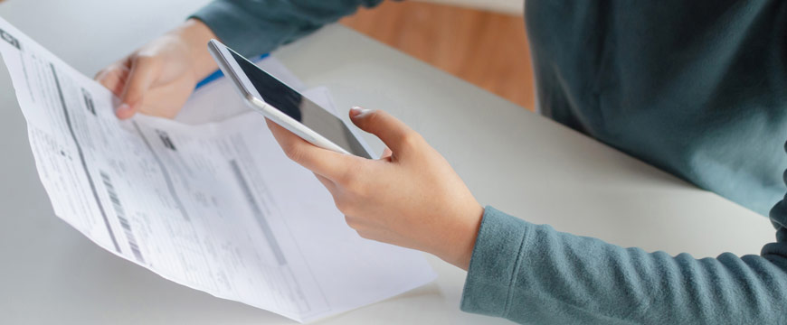 Woman using cell phone to pay a bill