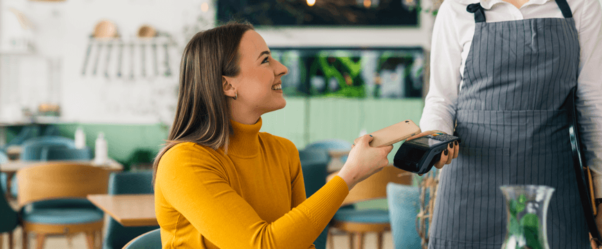 Woman using phone to pay at cafe