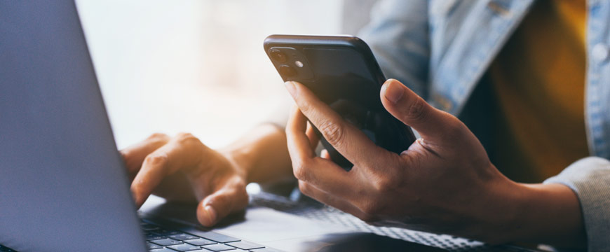 Woman using cell phone and laptop