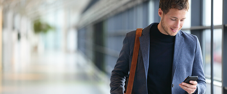 Text Banking, image of a young man texting on his cell phone, building in background