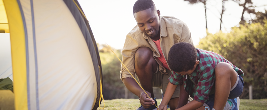 Father helping son put up tent