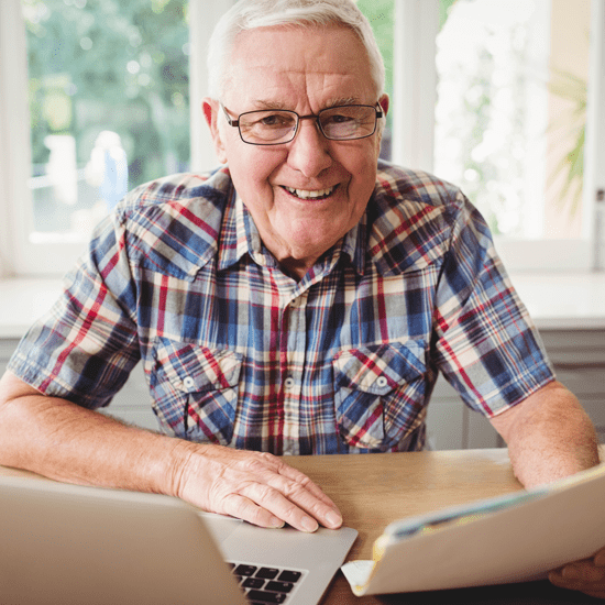 Man looking at laptop and paperwork