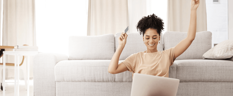 Woman holding debit card while looking at laptop