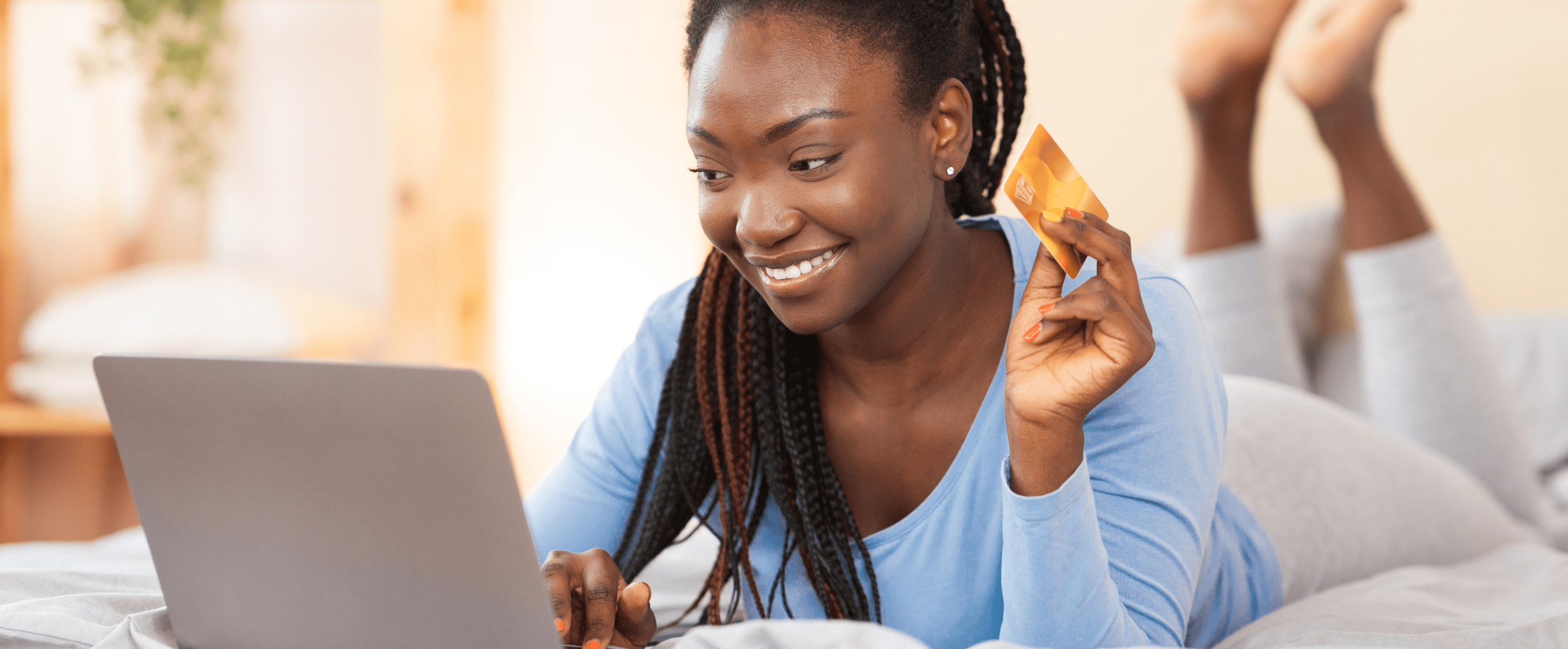 Woman holding debit card while looking at laptop