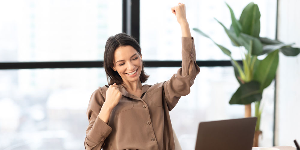 Woman making 'yes' gesture while viewing laptop